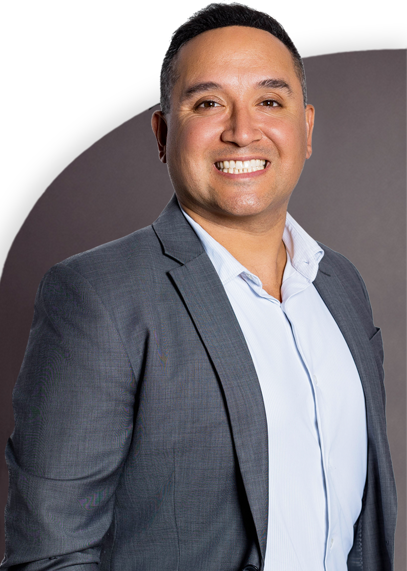 A man in a suit smiles against a dark background.