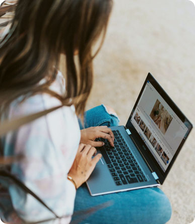 A person sits outdoors using a laptop with photo editing software open on the screen.