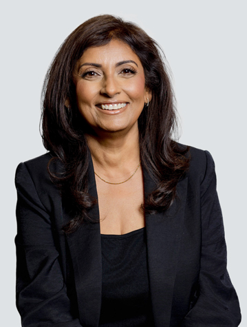 Smiling person in a black blazer and top, posing against a plain background.