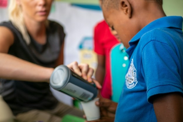 a woman giving a boy a drink at a food bank