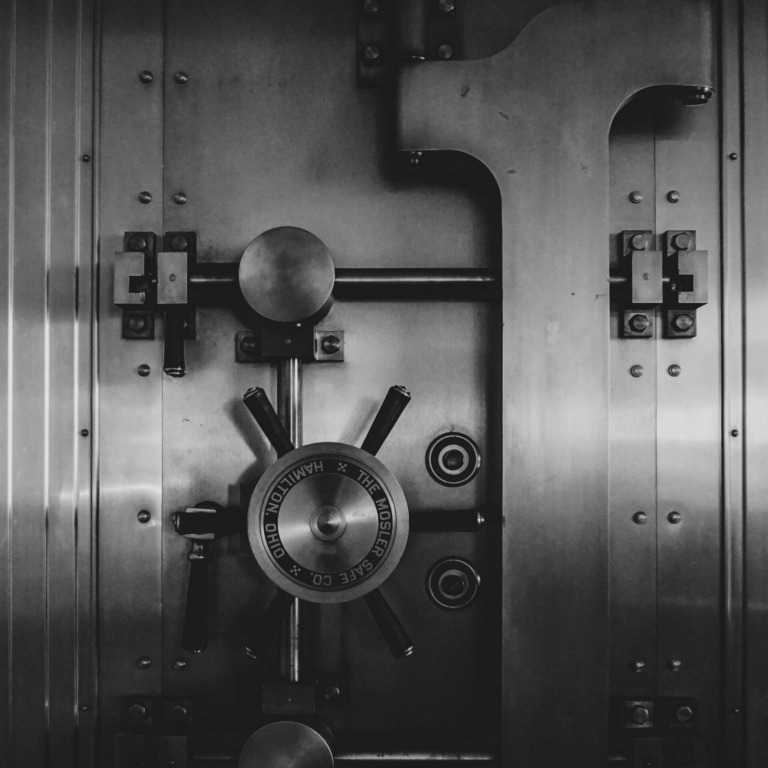 A close-up view of a large, intricate steel vault door with heavy locking mechanisms and the inscription "The Mosler Safe Co. Hamilton, Ohio.