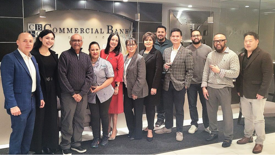 A group of people standing together in business attire at a commercial bank office, posing for a photo.