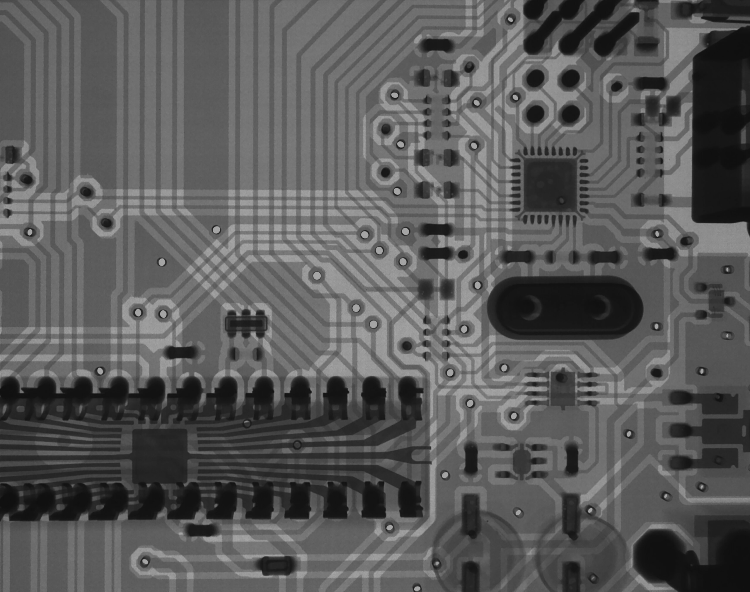 Close-up of a printed circuit board with visible tracks and components, including a microchip and various connectors.