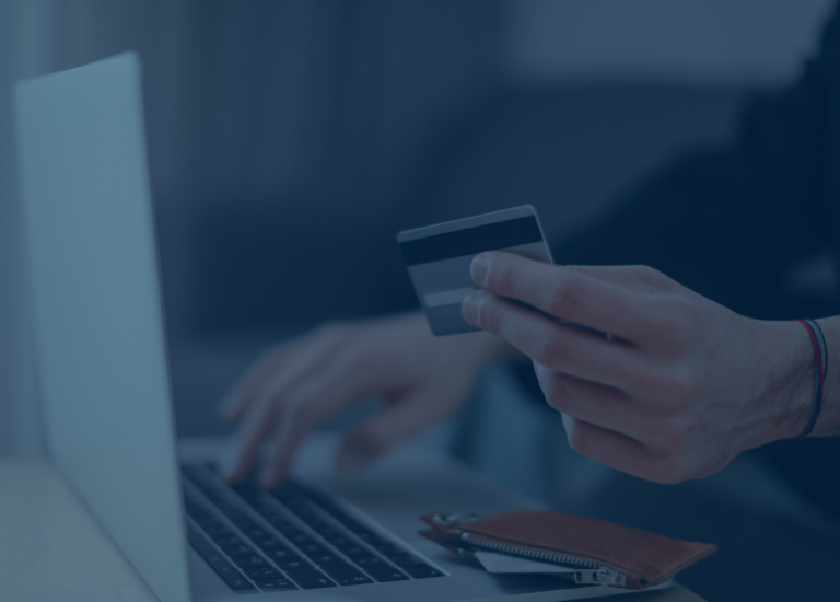 Person holding a credit card and typing on a laptop, with a wallet placed nearby, possibly researching interest rates before making an online purchase.