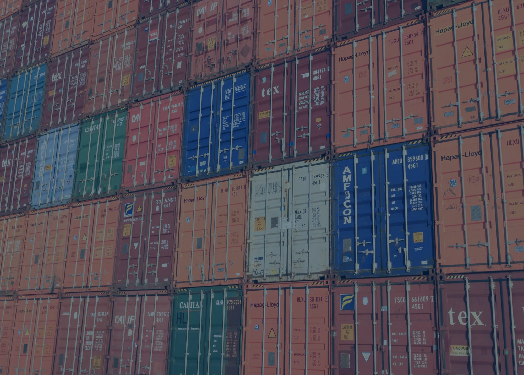 Stacked shipping containers in various colors are arranged in neat rows, creating a colorful and orderly pattern at a shipping yard—a lively scene influenced by shifting interest rates affecting global trade.